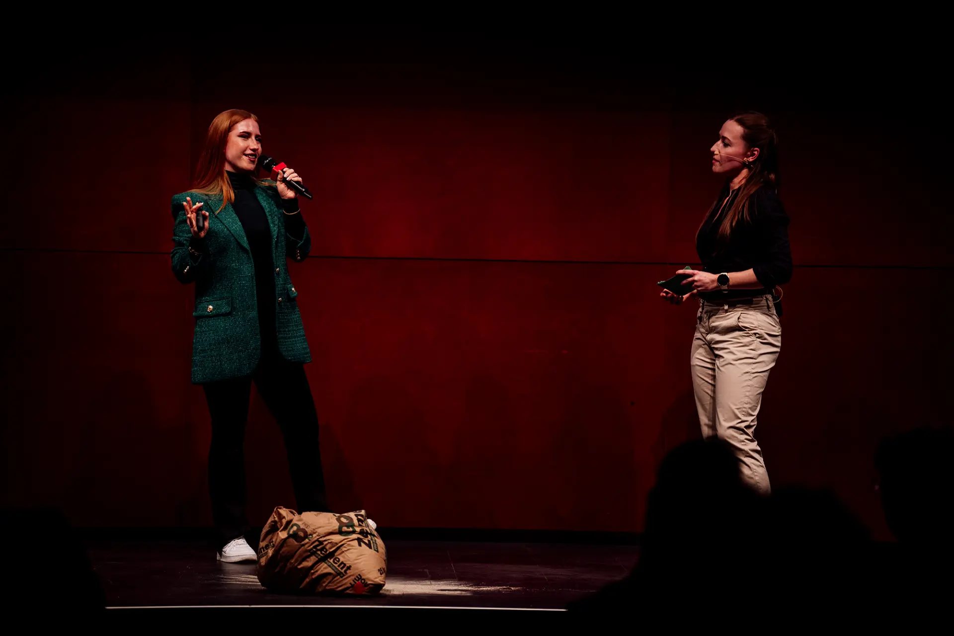 Eva-Maria Schneider in conversation with a host on a red-lit pitch stage
