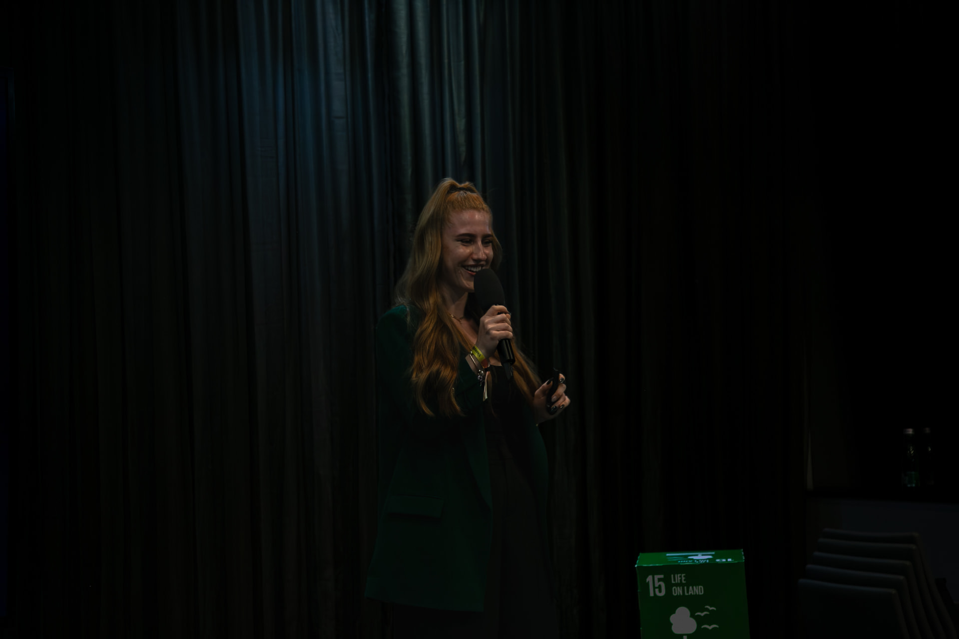 Eva-Maria Schneider speaking on a dark stage next to a sustainability goal cube